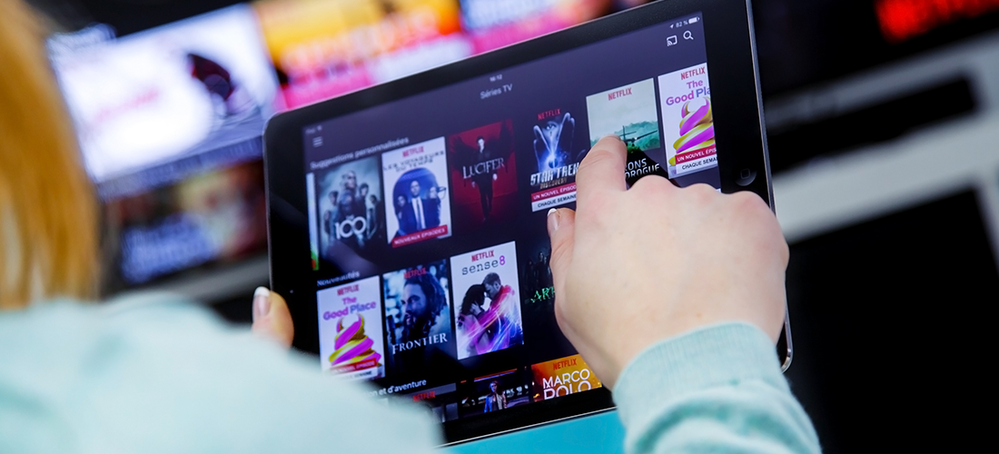 a person using a tablet views the thumbnails of potential shows or movies they can watch via a streaming platform