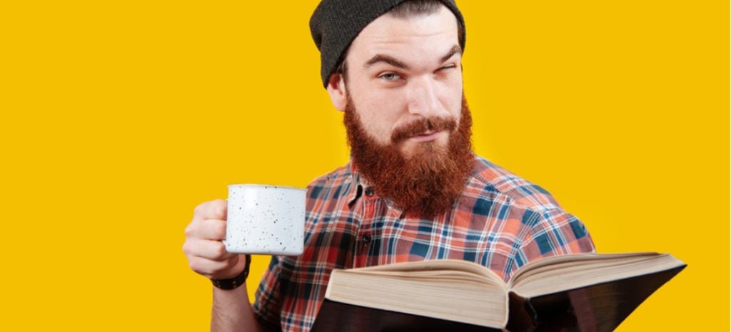 Bearded man looking something up in a large book