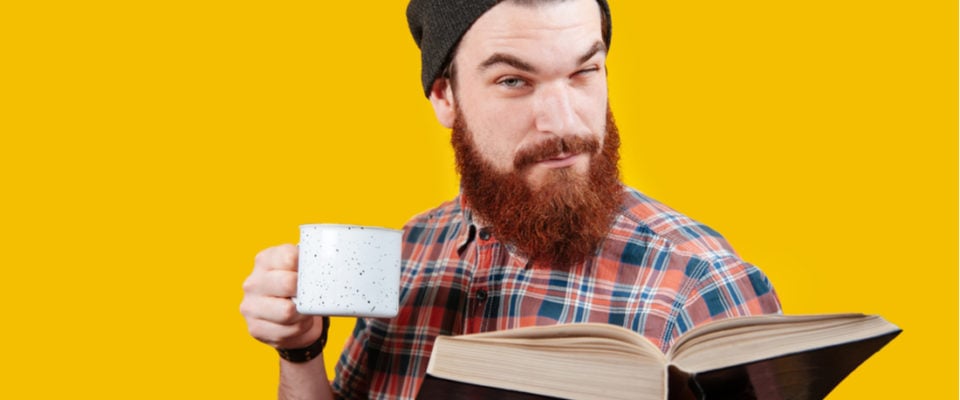 Bearded man looking something up in a large book