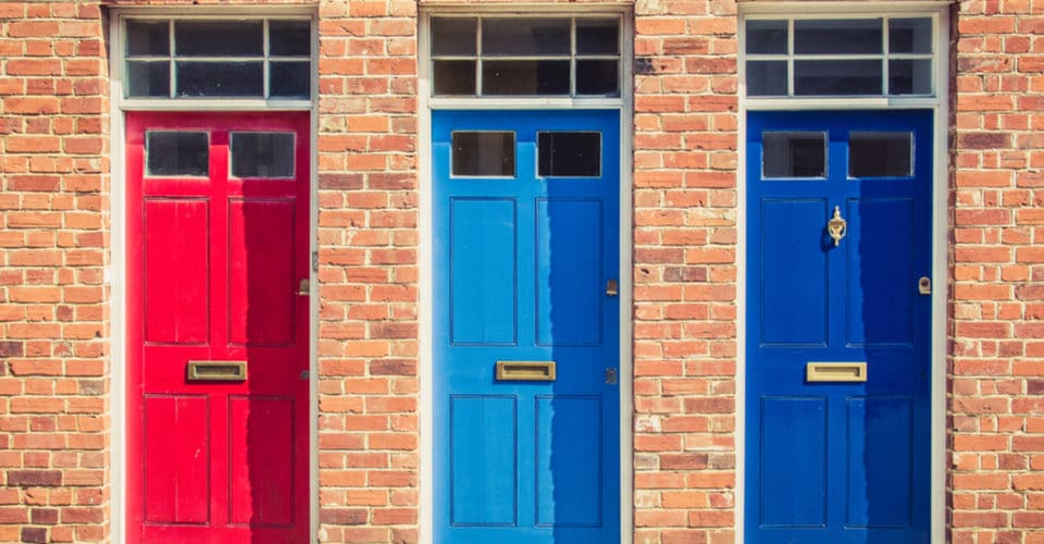 A red, light blue, and dark blue door on a brick building