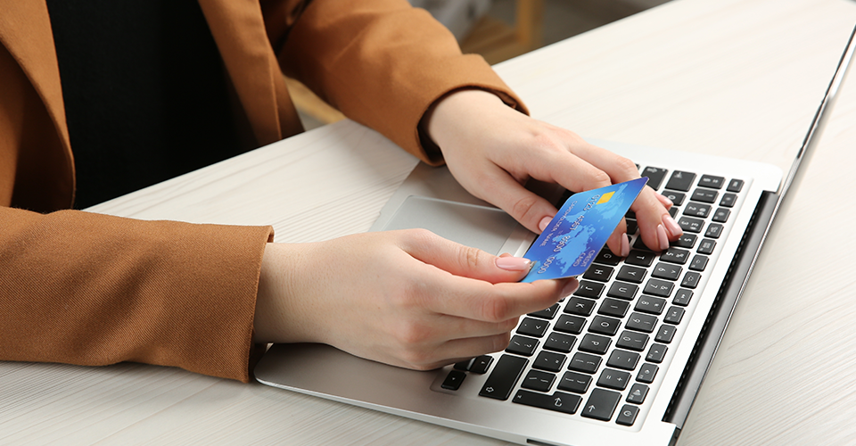 a woman uses a credit card to buy from an eCommerce site on a laptop