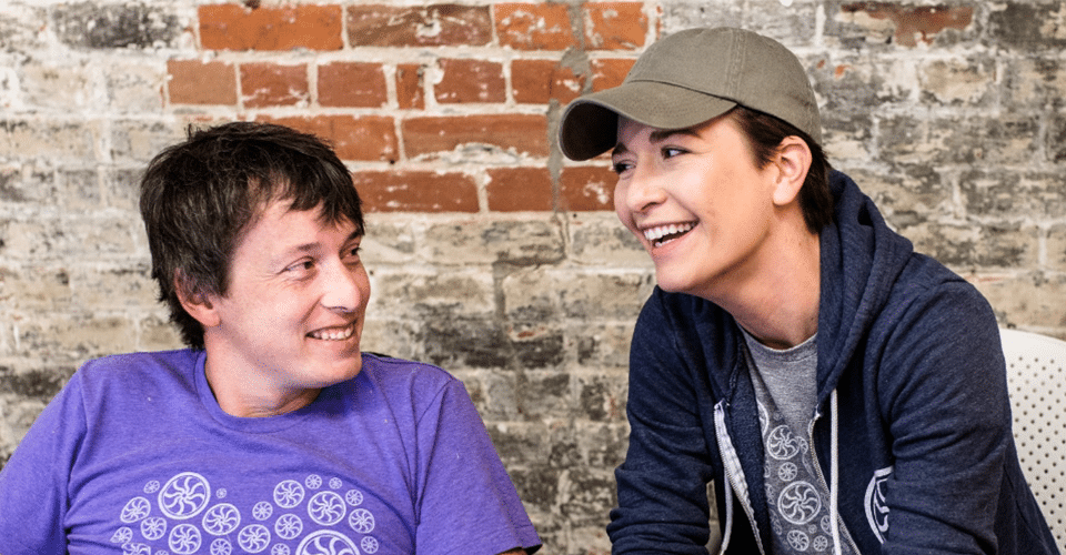 two people discuss a design project in front of a brick wall