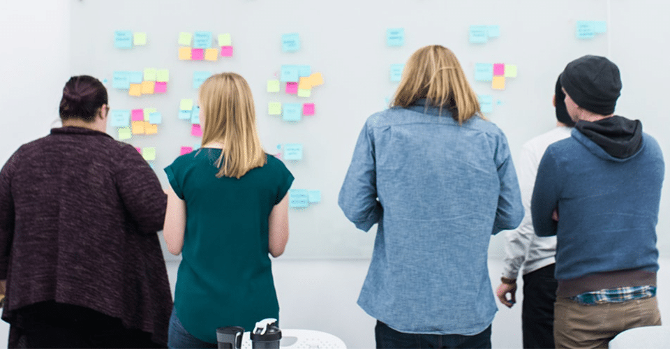 a marketing team defines their content strategy using sticky notes on a large white wall