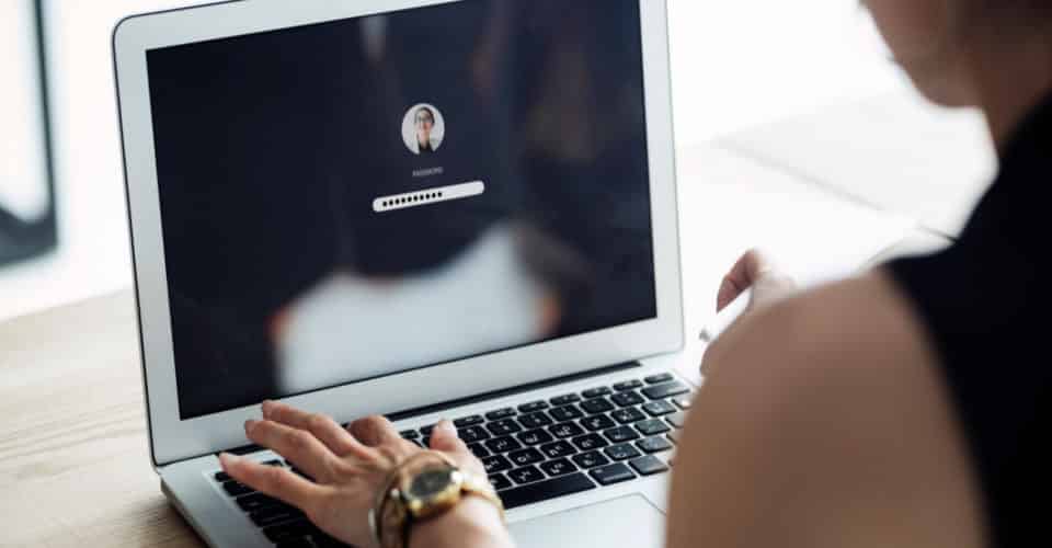 woman typing password on laptop