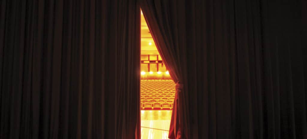 slightly open stage curtain looking out at theatre