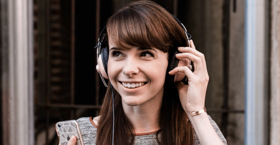 a creative smiles while removing her over-the-ear headphones