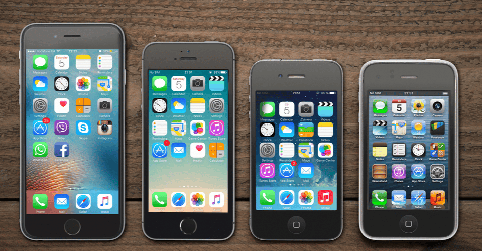 Front view of a space grey color iPhones 6, 5s, 4 and 3gs generation showing the home screens on wooden background