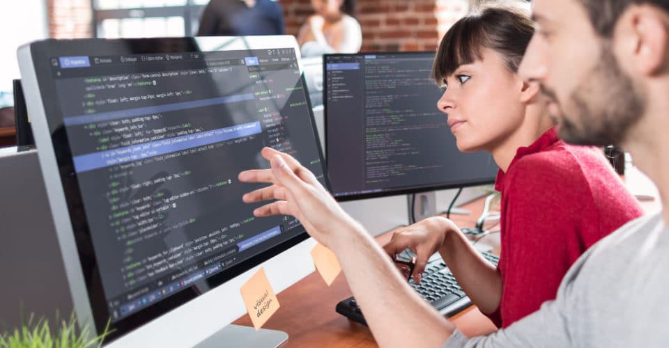 two people looking at code on a computer screen