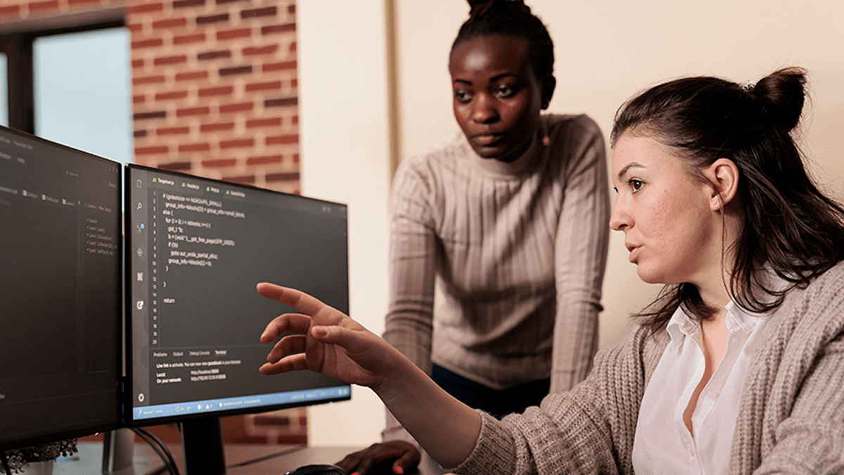 JavaScript for WordPress. Two women work on Javascript code at a dual monitor desktop